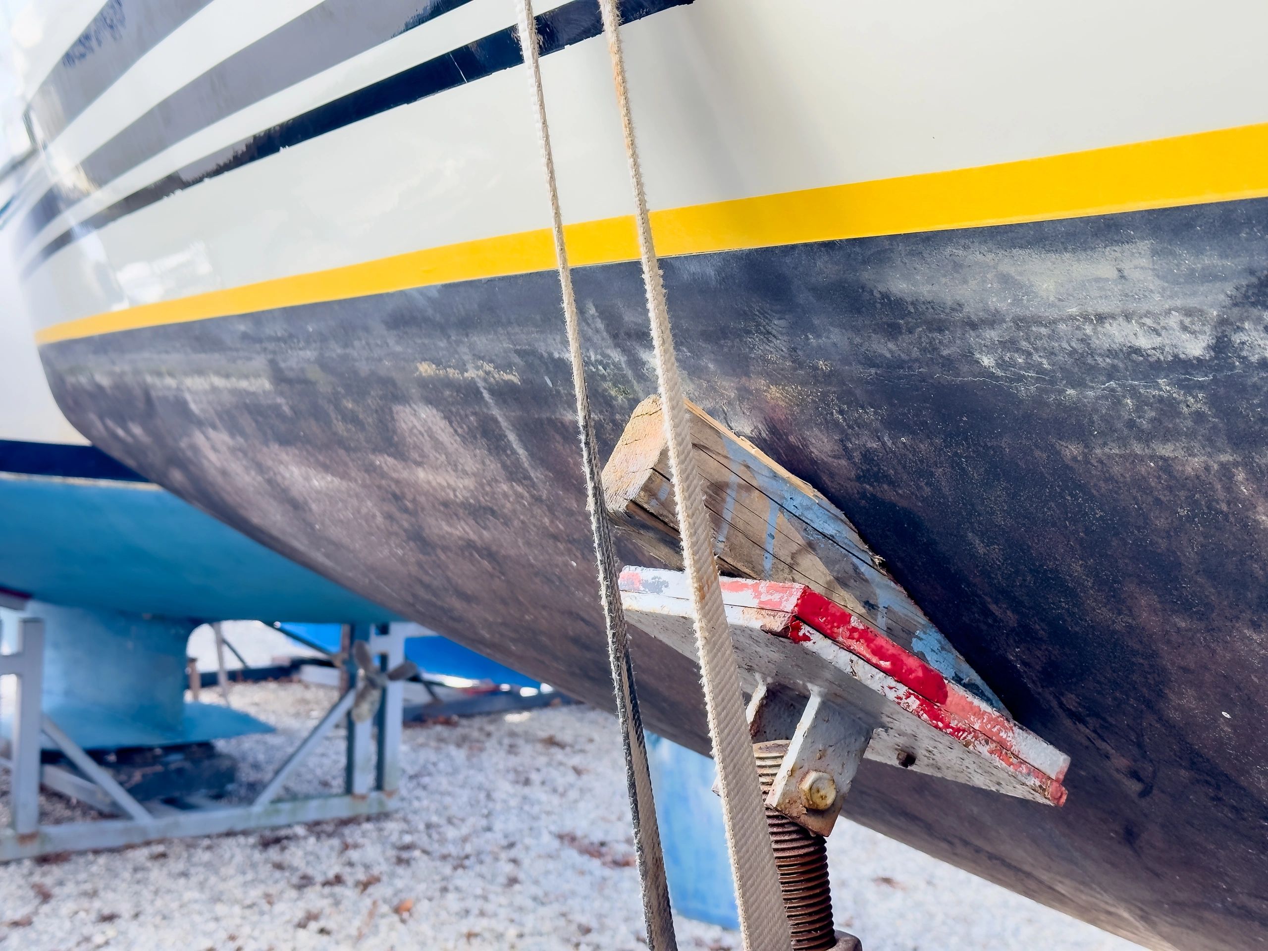 Sailing boat on stilts being painted with antifouling